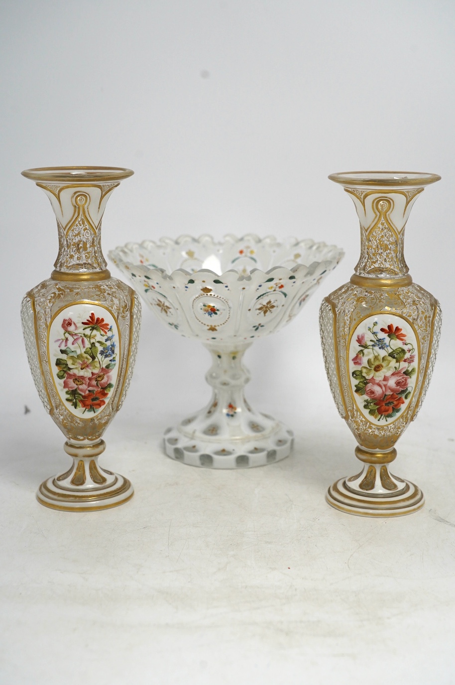 A pair of late 19th century Bohemian enamelled overlaid glass vases, and a similar overlaid glass comport. Condition - vases fair; comport poor